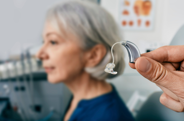 A Horizon Hearing specialist presenting a behind-the-ear hearing aid, emphasizing the importance of regular hearing aid maintenance for optimal performance.