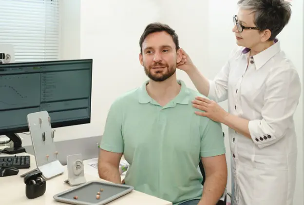 Audiologist fitting a hearing aid for a male patient at Horizon Hearing Centre.